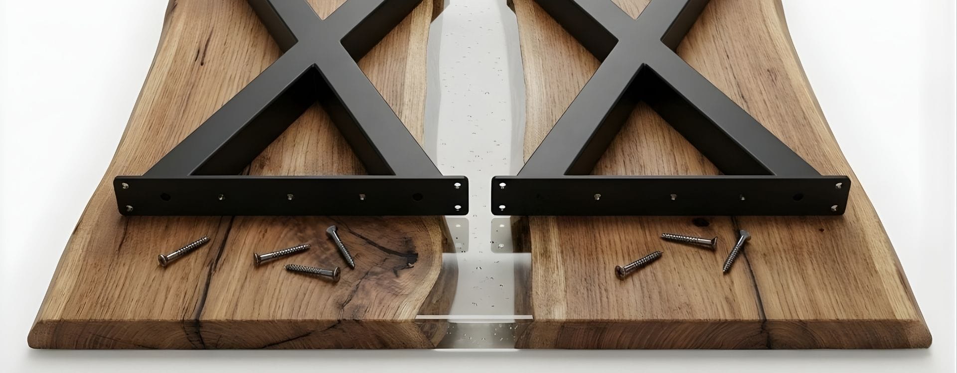 Vista inferiore del tavolo capovolto con gambe in ferro ad X già fissate al piano in legno massello e resina, dettaglio tecnico del montaggio – Decimus.